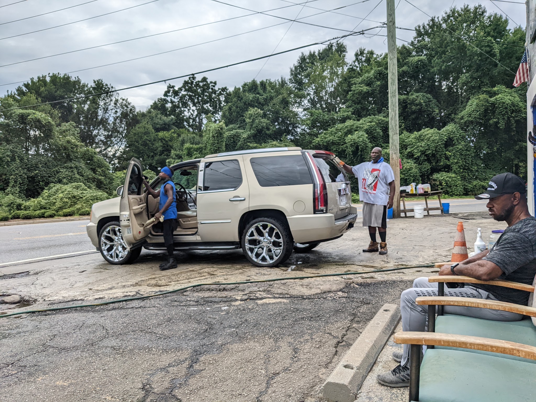 Our crew hand washing a tan Cadillac Escalade on the forecourt, with seating for customers beside it