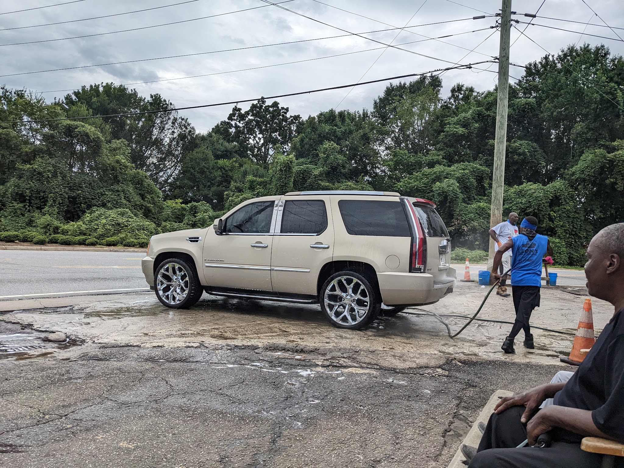 A tan Cadillac Escalade on chrome wheels being rinsed down